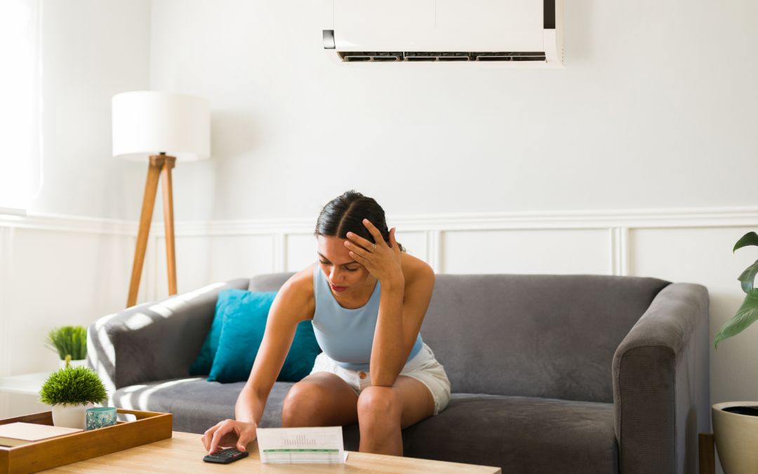 A homeowner sits on her sofa in a hot house, dialing the number for an emergency AC repair company in West Palm Beach